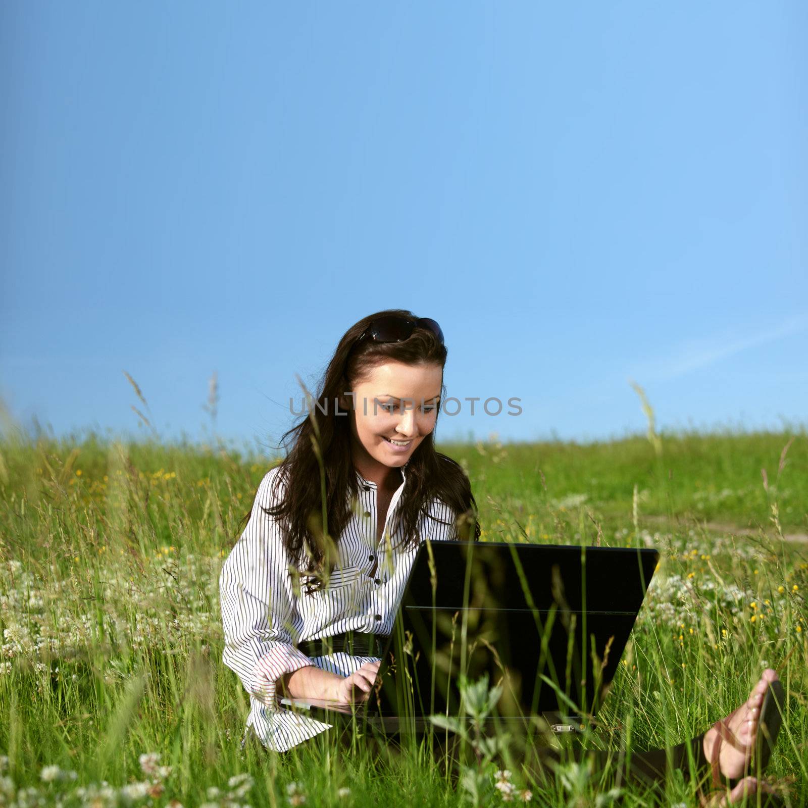 woman on green field work on laptop