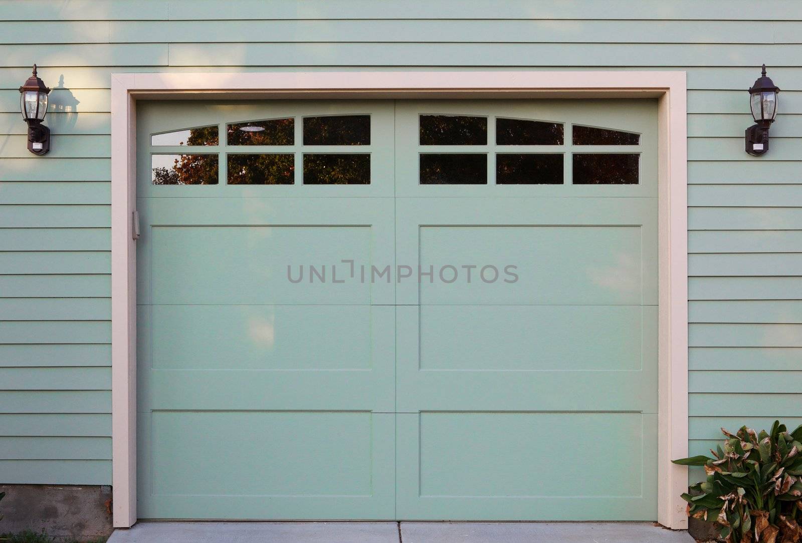 Light green garage door with windows and two lanterns
