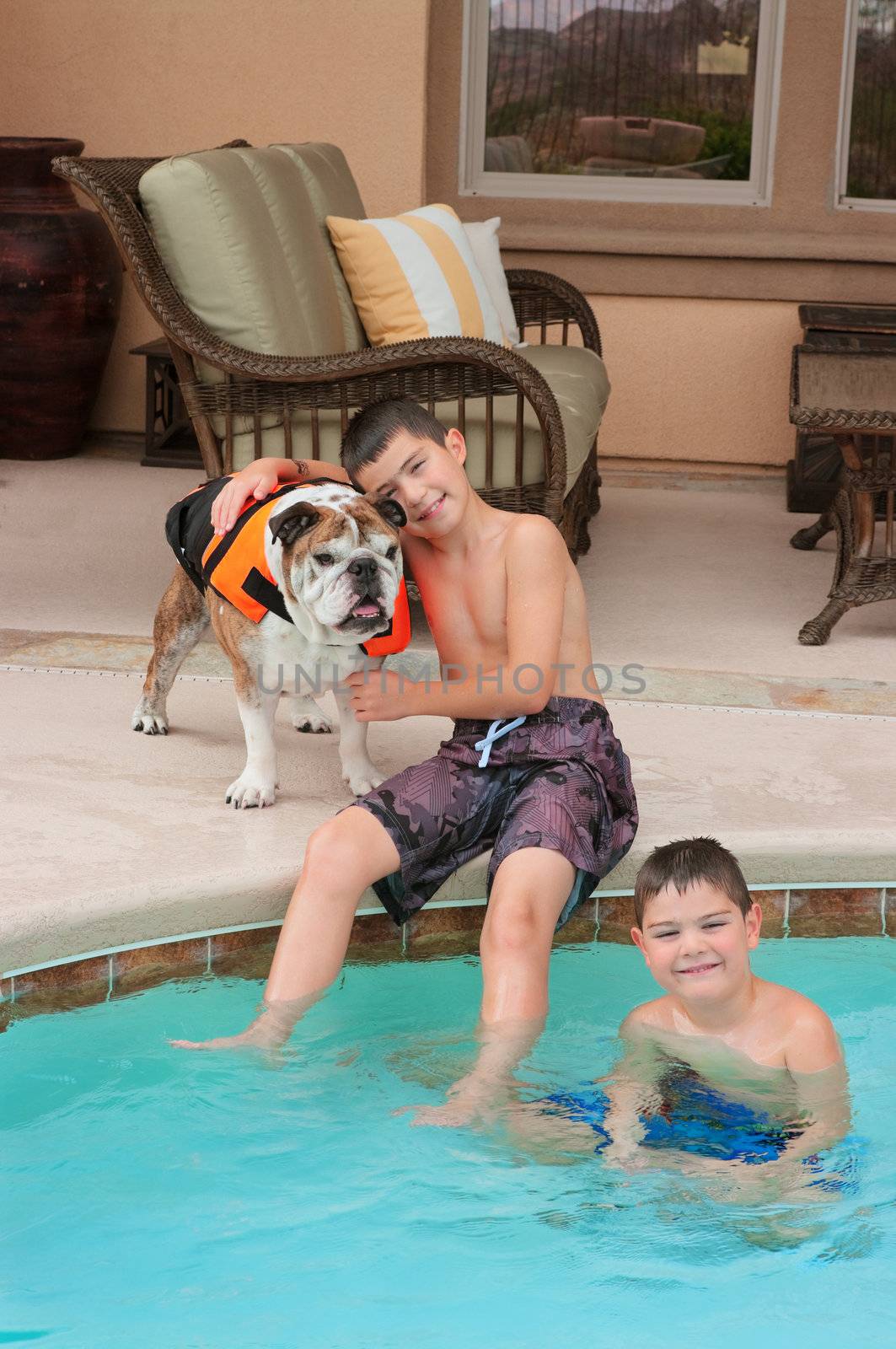 Kids and their pet bulldog playing near the pool
