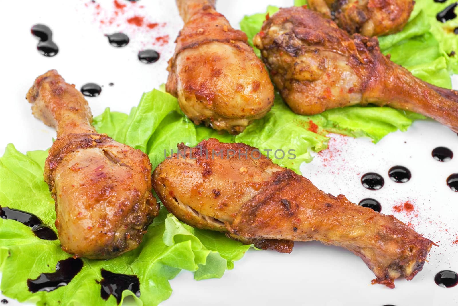 chicken drumstick closeup at white plate with lettuce