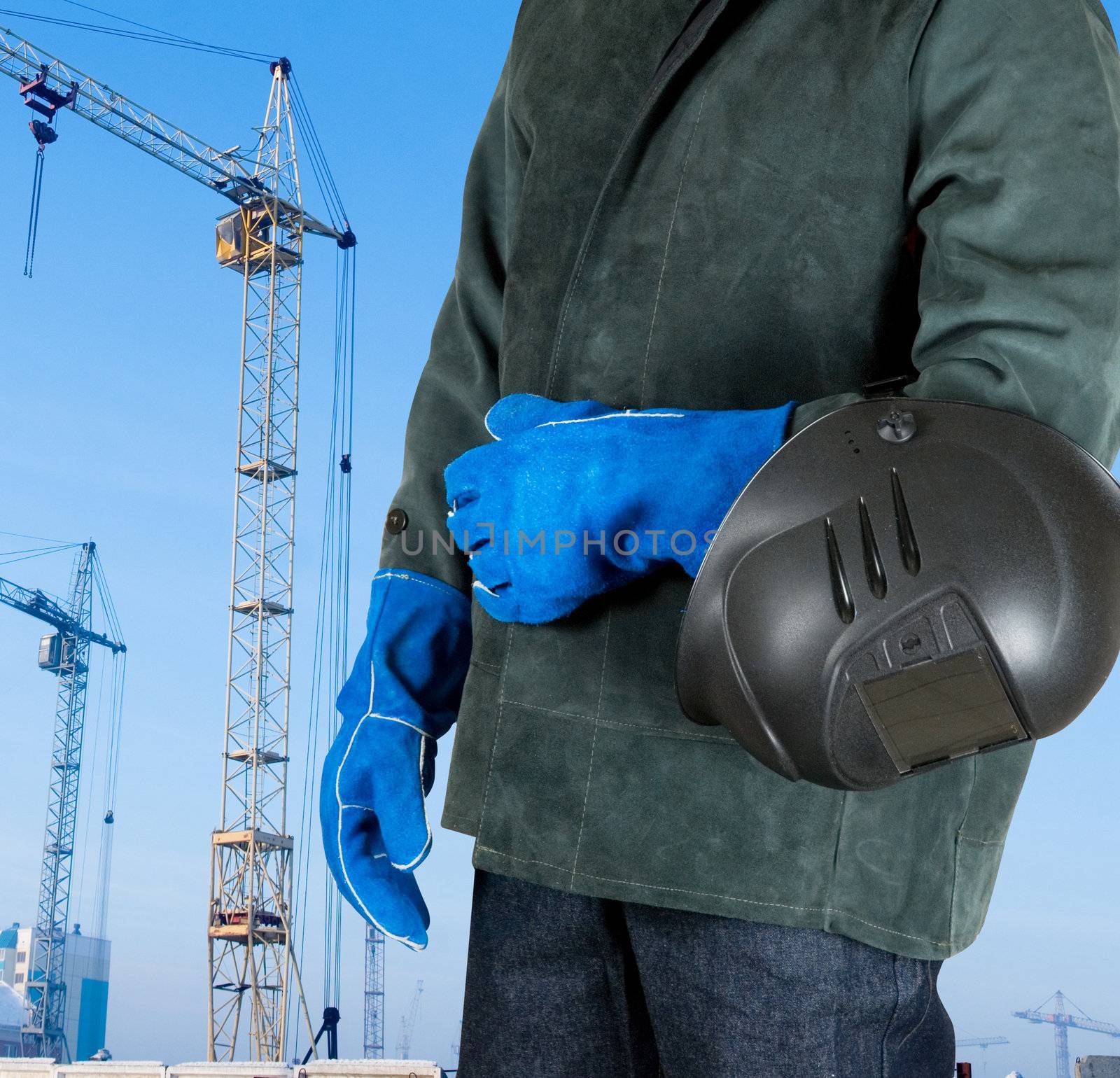 male welder closeup with welding equipment on building background