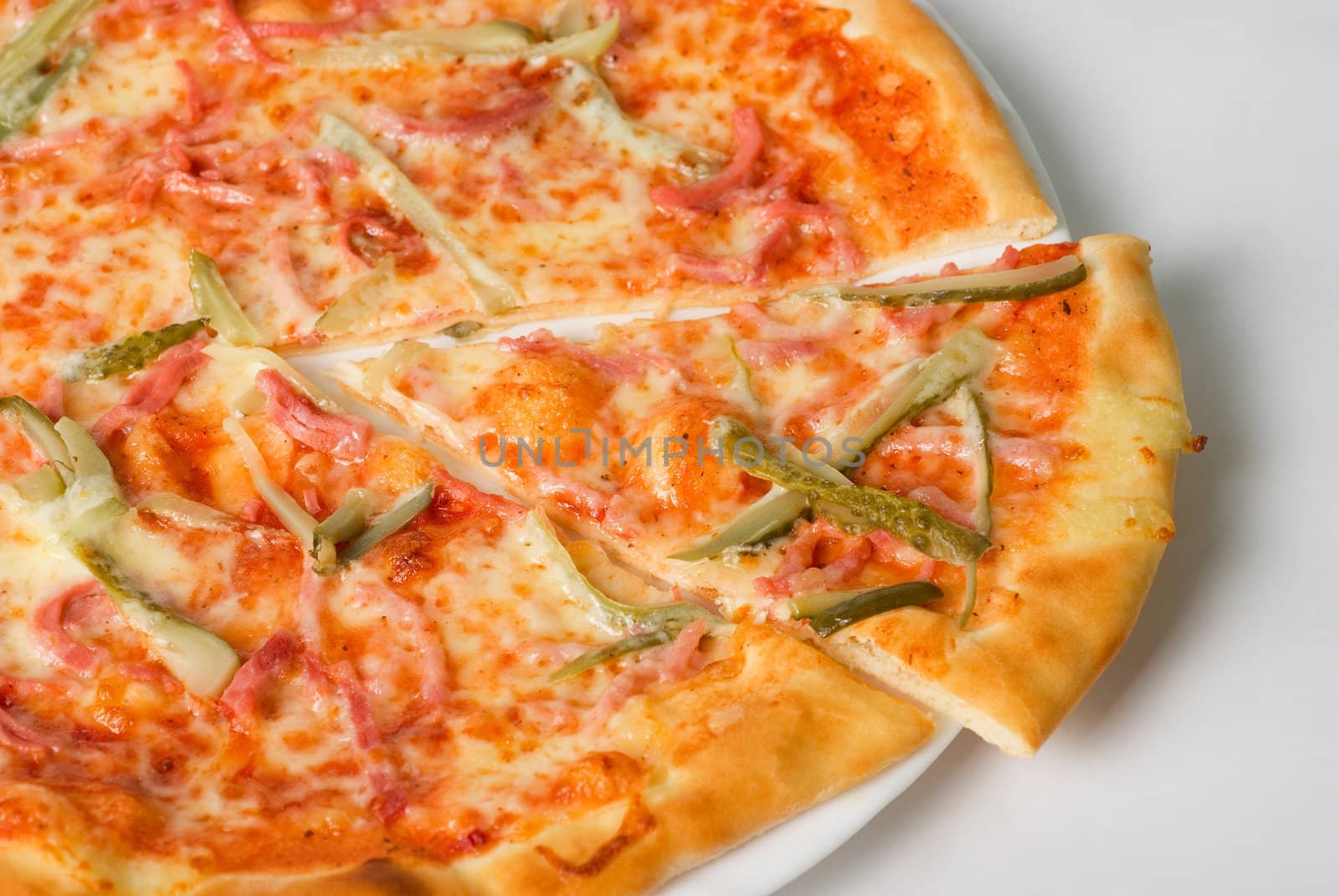 pizza closeup with boiled sausage, ham, marinated gherkin and mozzarella cheese