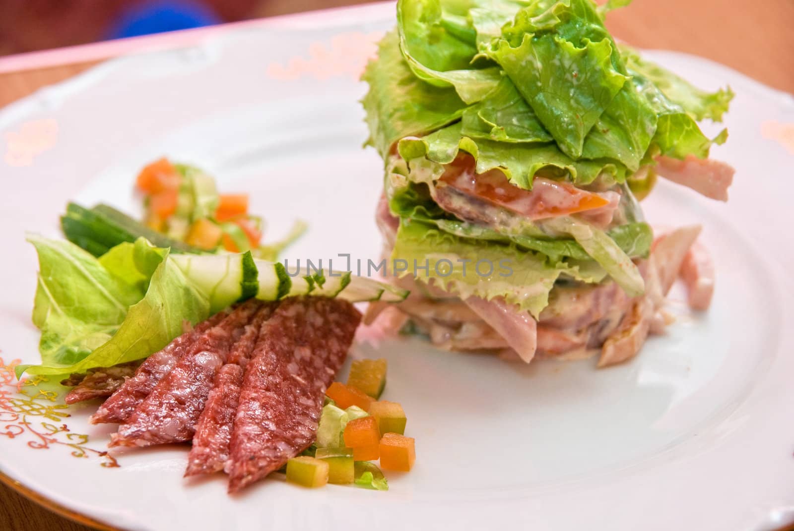 Salad from different kinds of sausages, cucumbers, peppers, lettuce with sour cream sauce