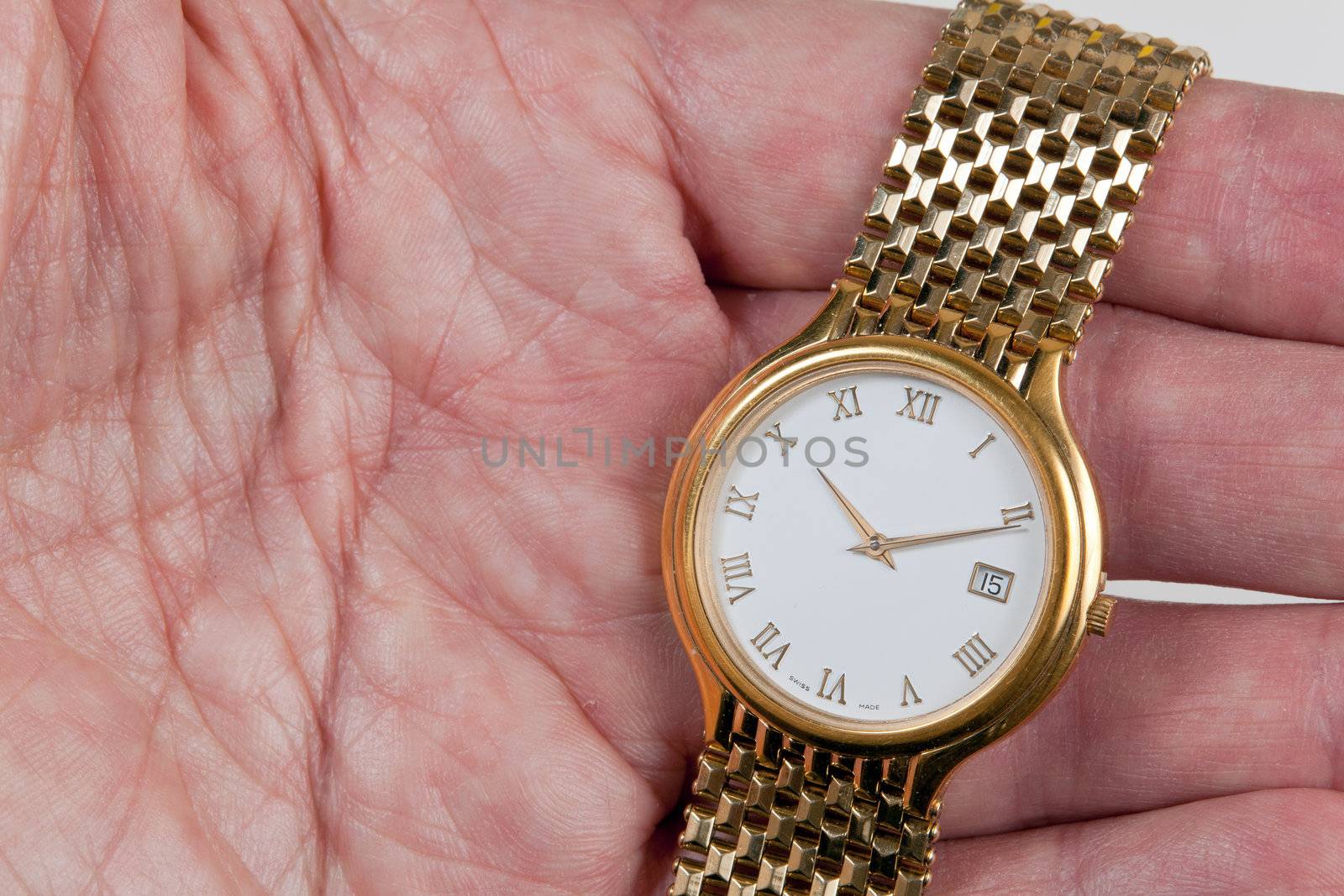 Gold watch and band in close up in palm of hand across fingers