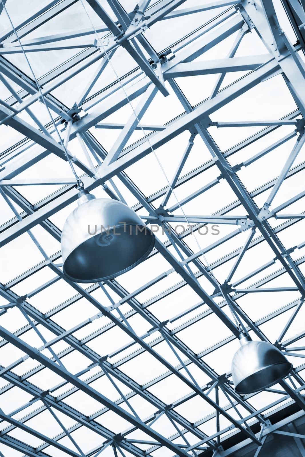 blue toned lamps and metallic girders under glass ceiling of industrial building