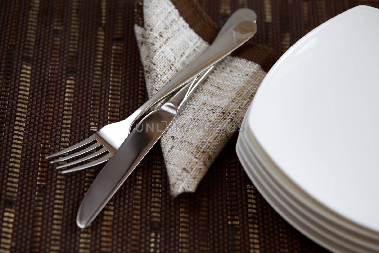 Table layout with tableware and a napkin on dark background