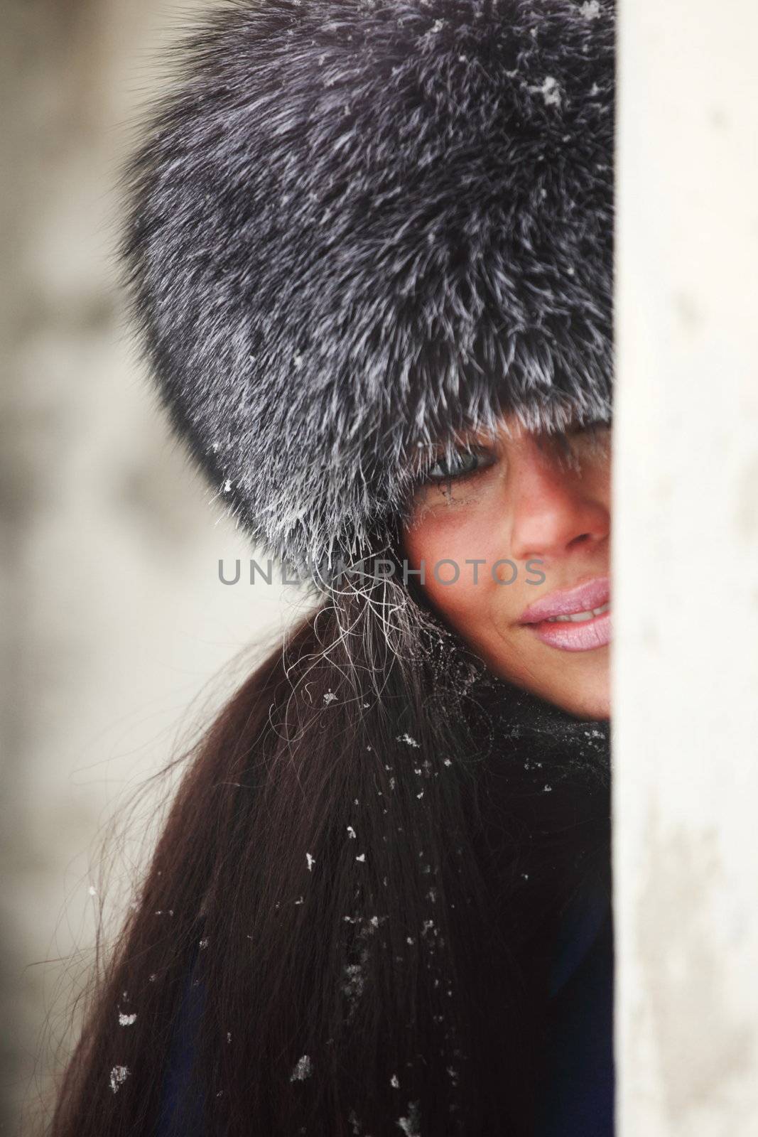  woman in fur hat hide behind column