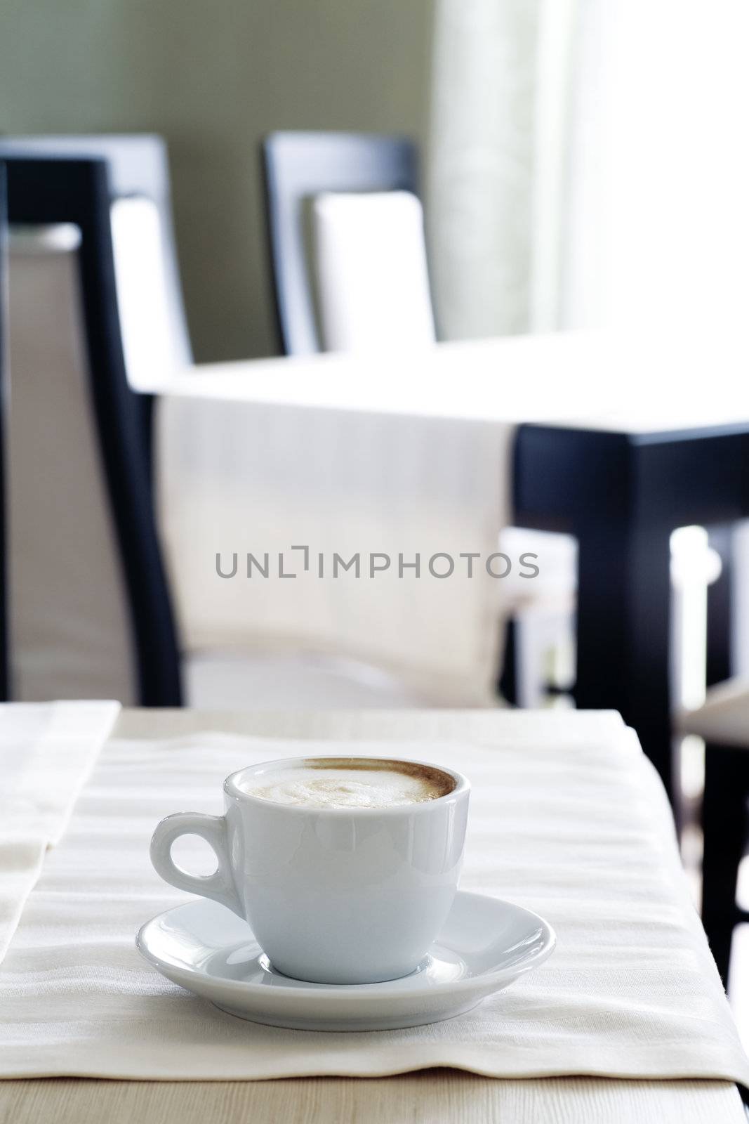 White cup of coffee in empty cafe in middle of the day