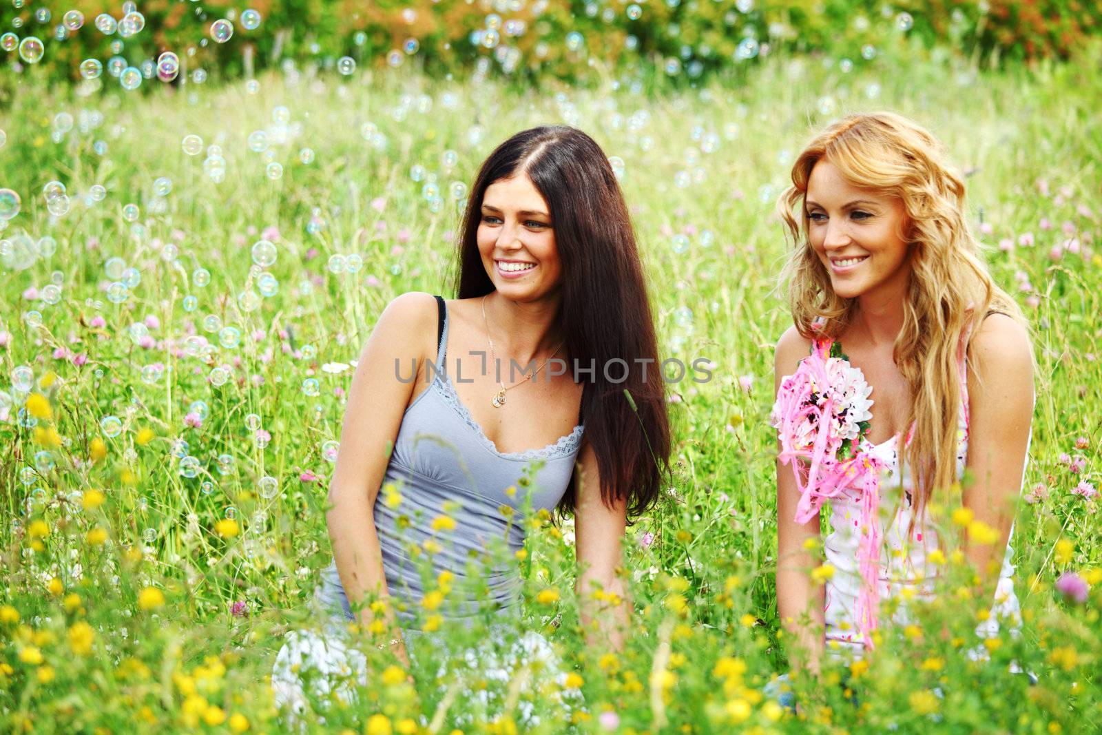 girlfriends on green grass field in soap bubbles