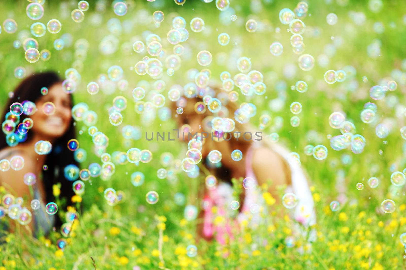 girlfriends on green grass field in soap bubbles