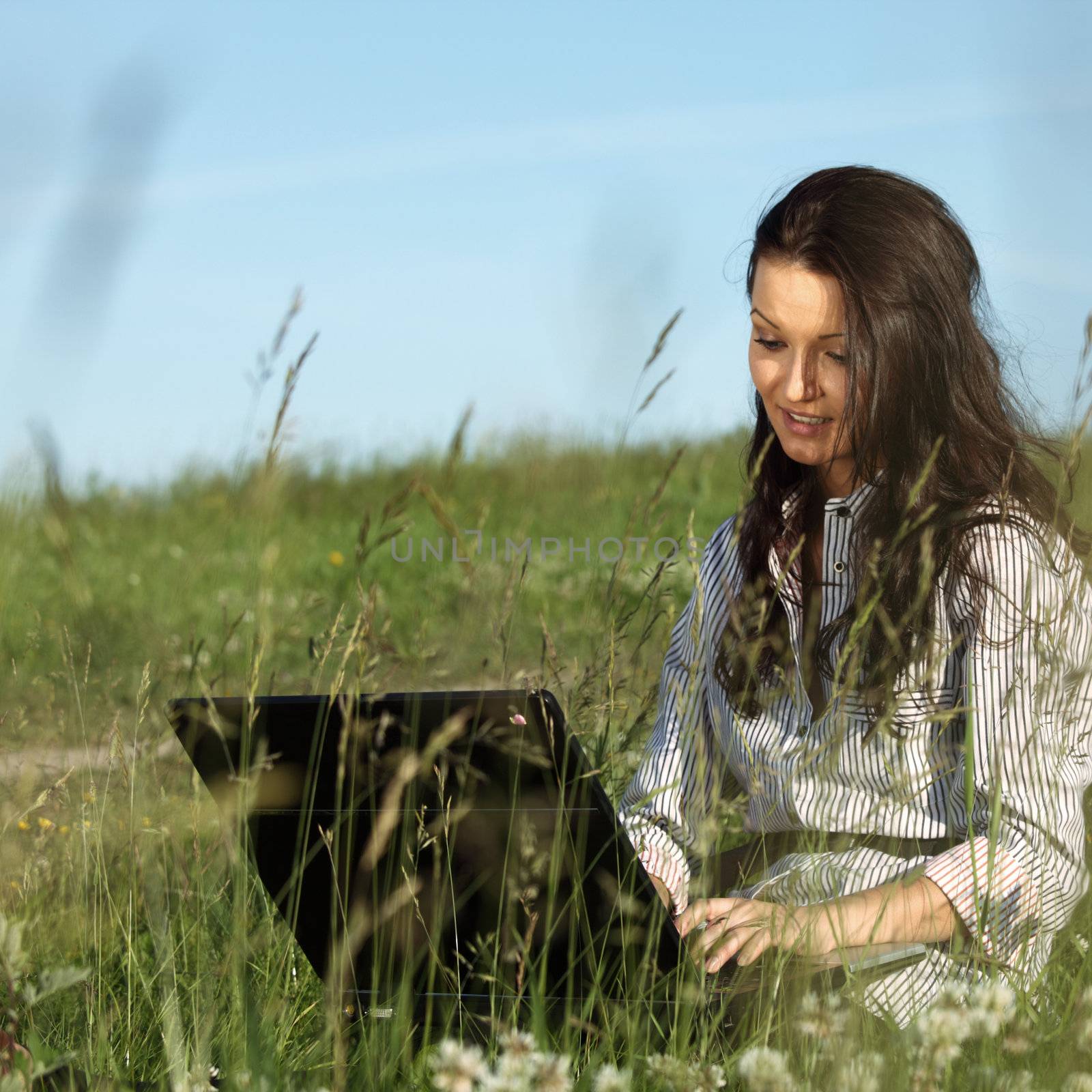 girl with laptop on green grass