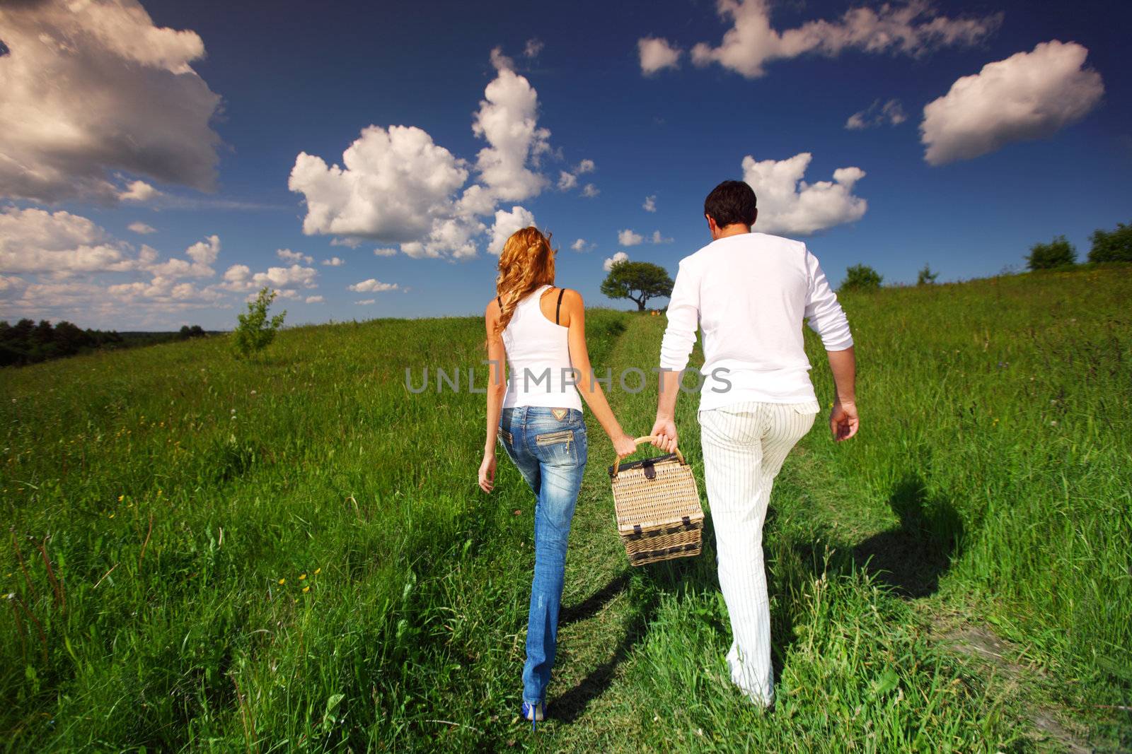 man and woman walk on picnic in green grass