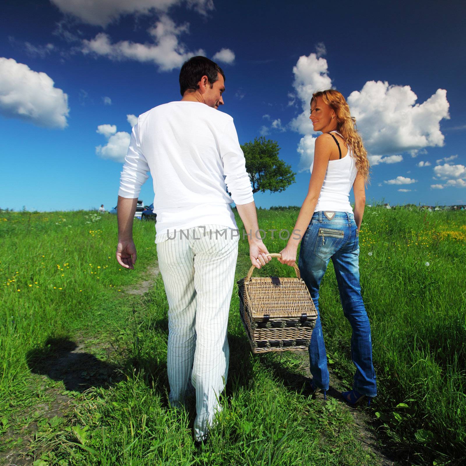 man and woman walk on picnic in green grass