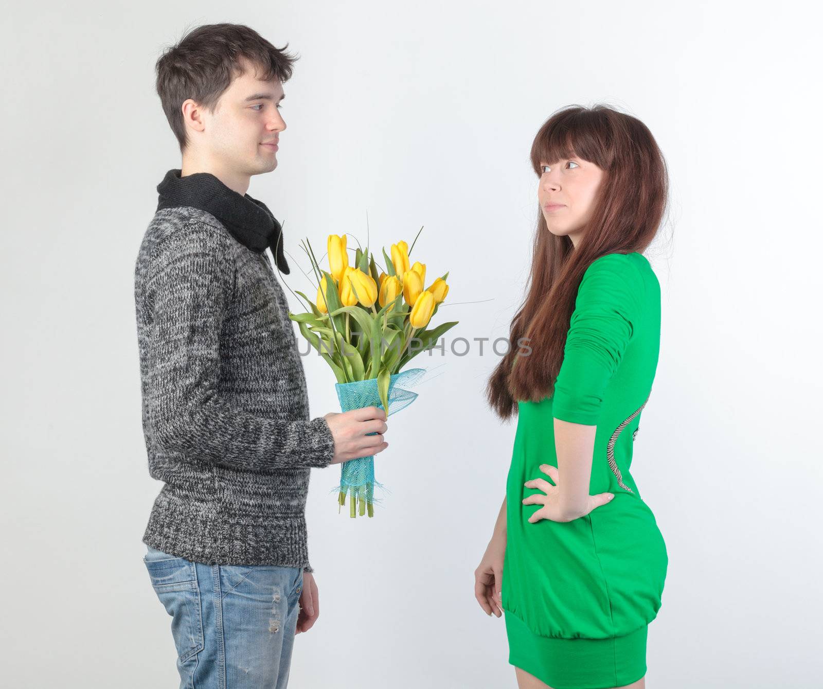 happy young couple with bouquet flowers, on gray background