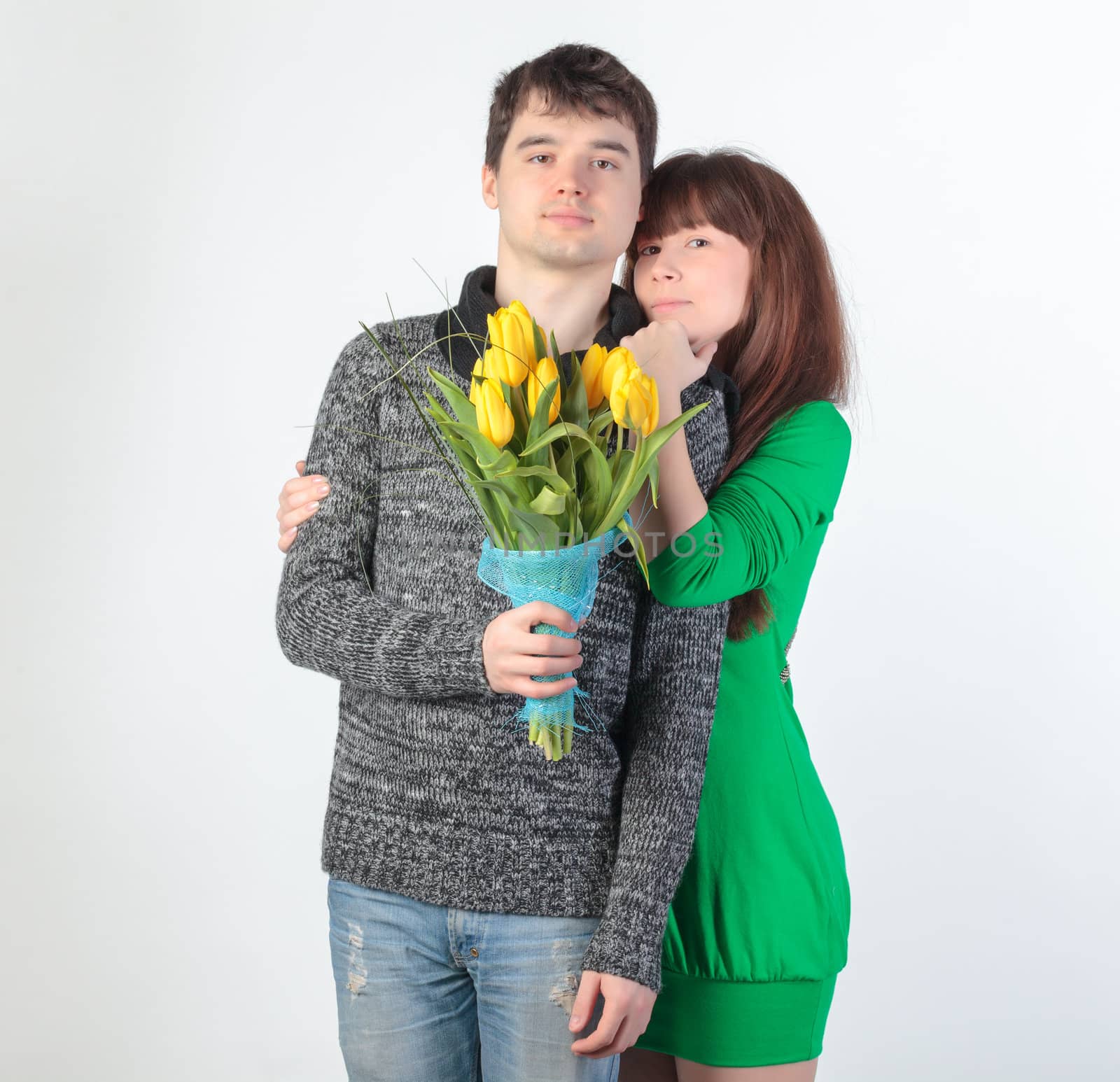 happy young couple with bouquet flowers, on gray background