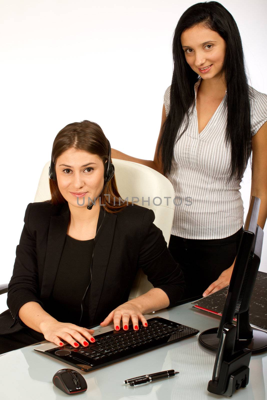 Two office women working together on a computer at their office desk