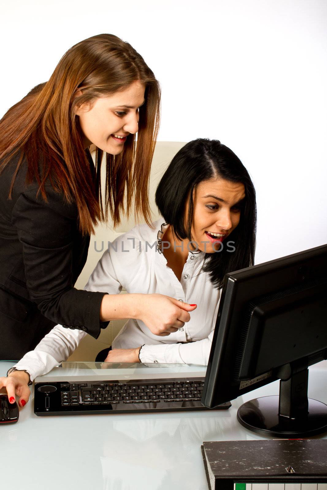 Two office women working together on a computer at their office desk
