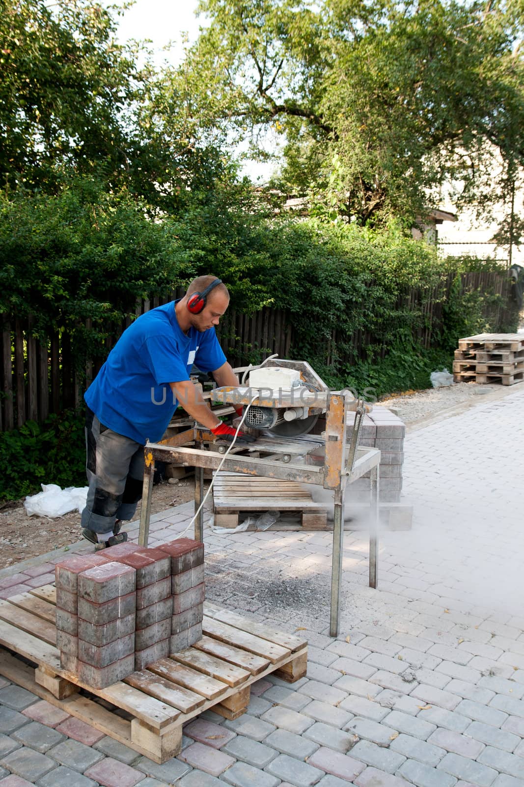 worker with circular saw sawing bricks for new street