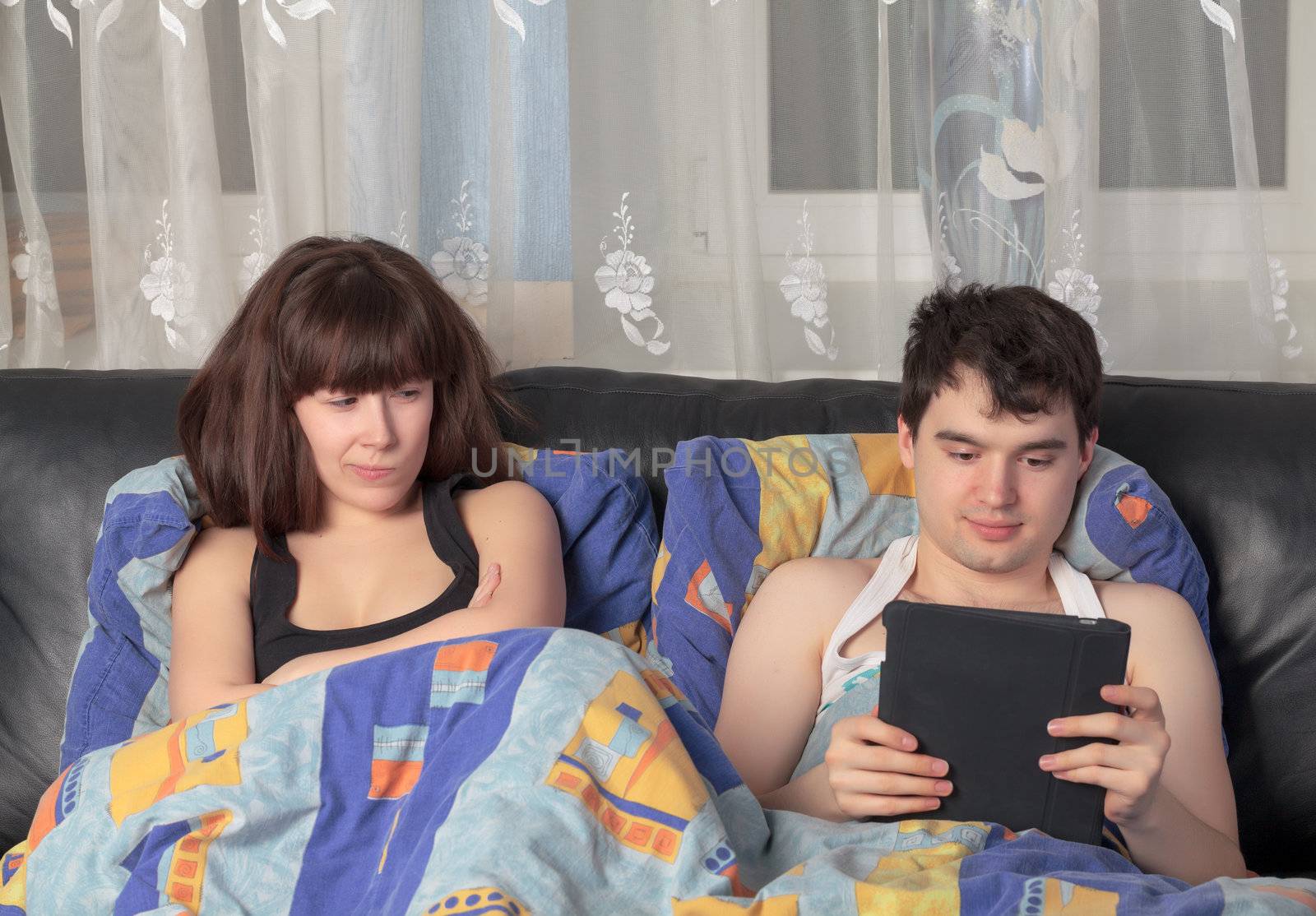 Young couple with tablet PC in their bed by Discovod