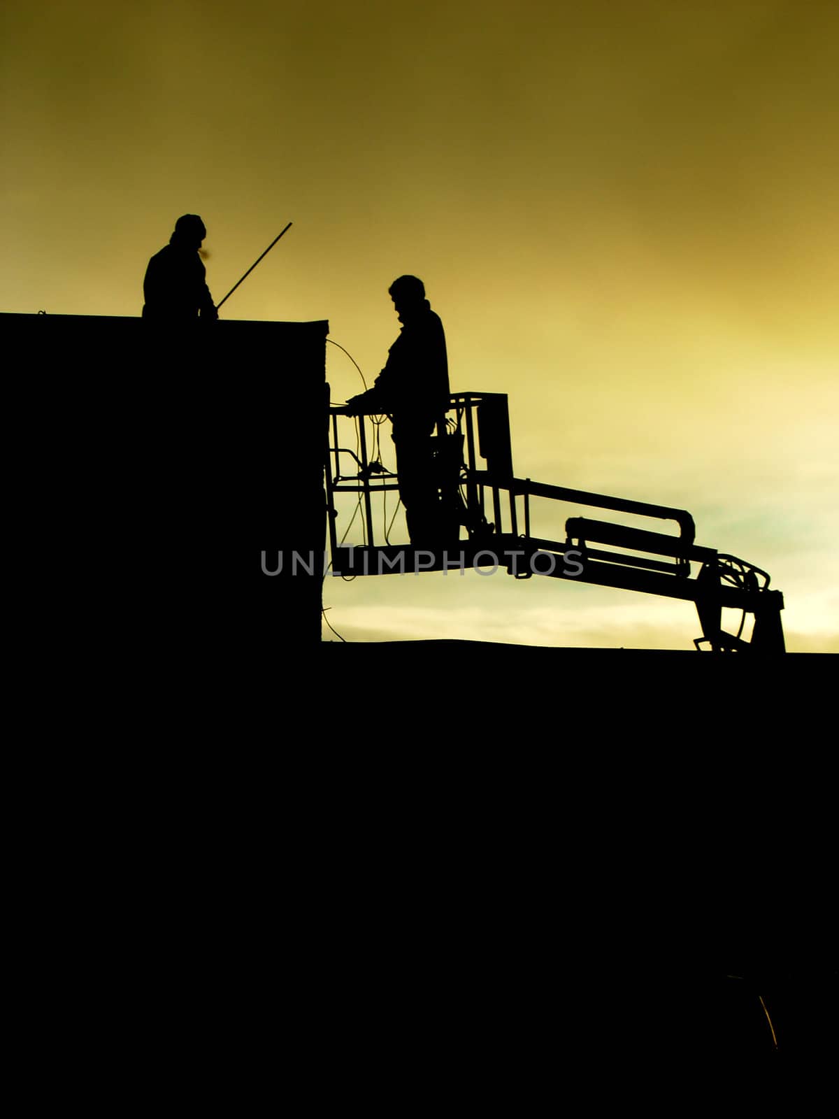 Silhouettes of men working at night.
They are working on a roof, one worker is in a lift