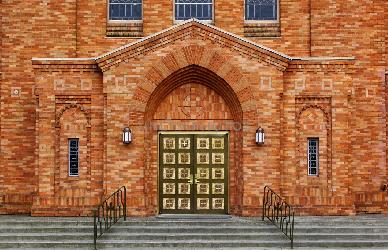 Green brass doors and orange brick facade of the front of a Greek Orthodox Church