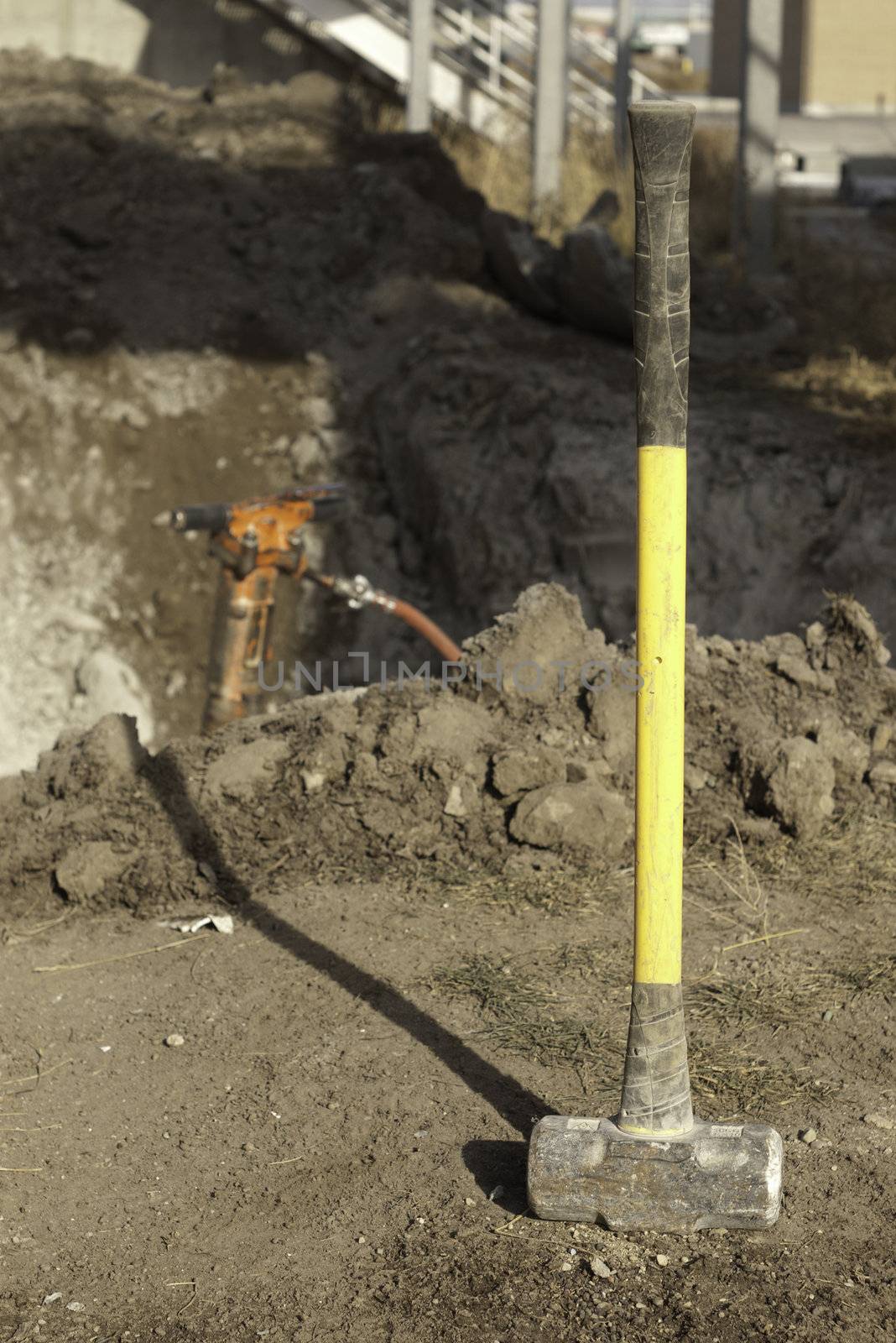 yellow sleg hammer on construction site with a jack hammer in the background