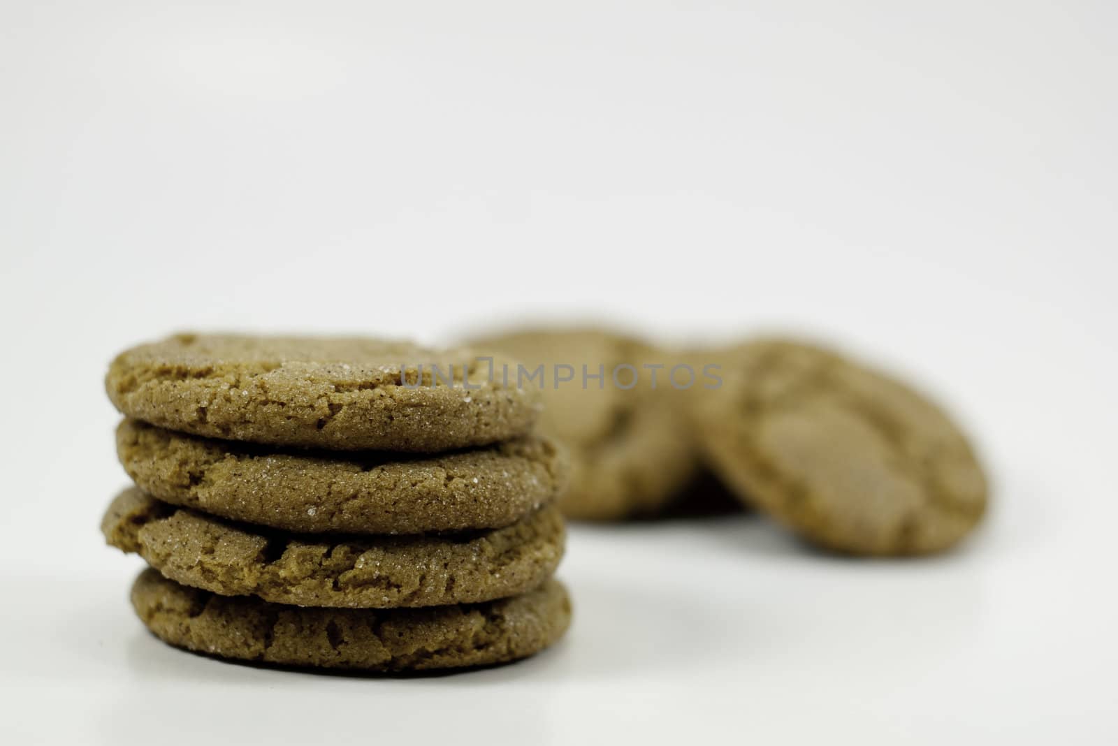 stack of four ginger snap cookies with cookies in the background shallow depth of field