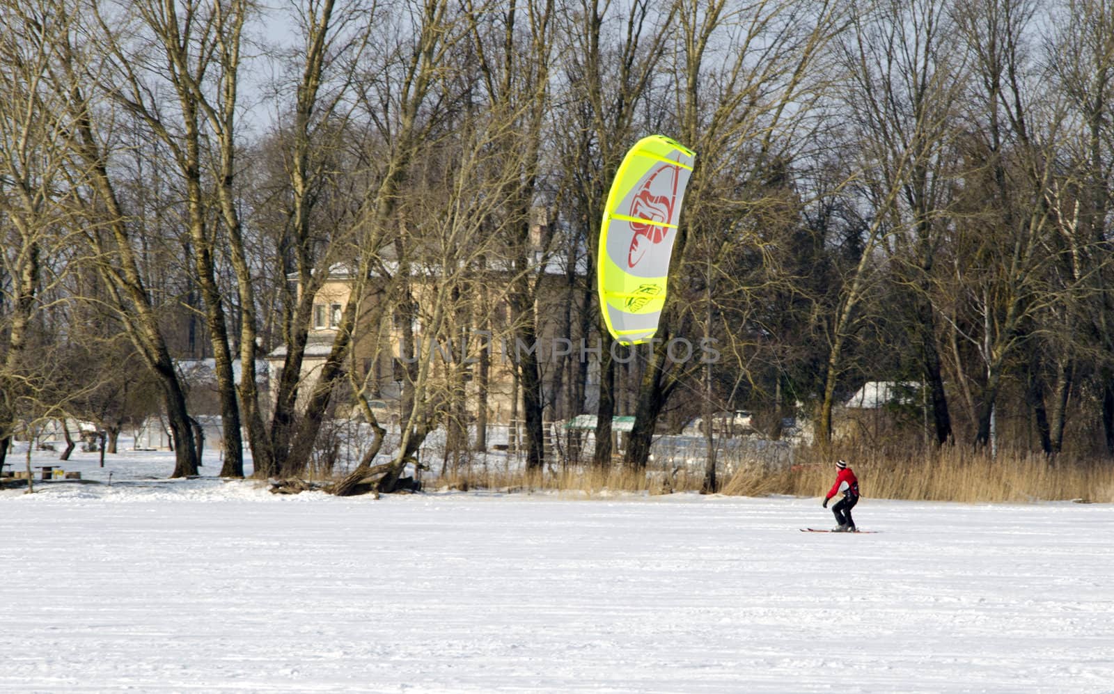 Man kiteboarding on frozen lake in winter. Original active outdoor recreation.