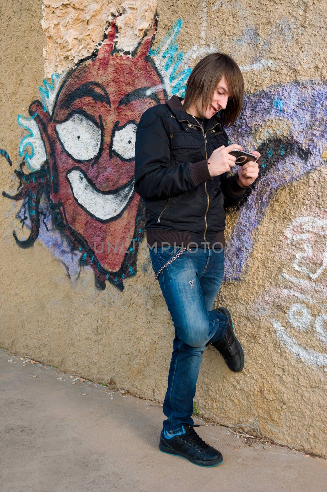 Teen playing with a console in a grunge urban setting