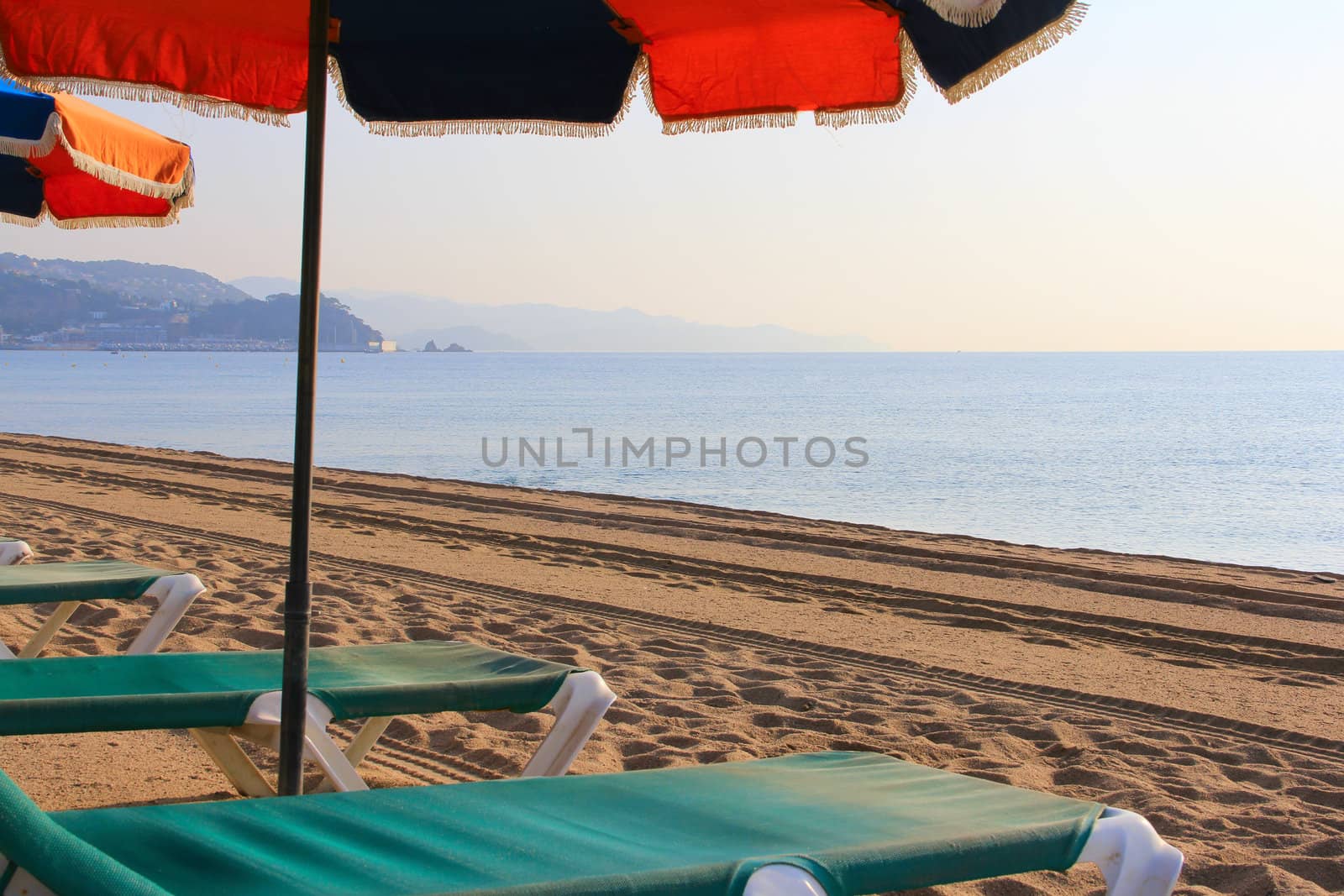Beach chair and umbrella on beach by destillat