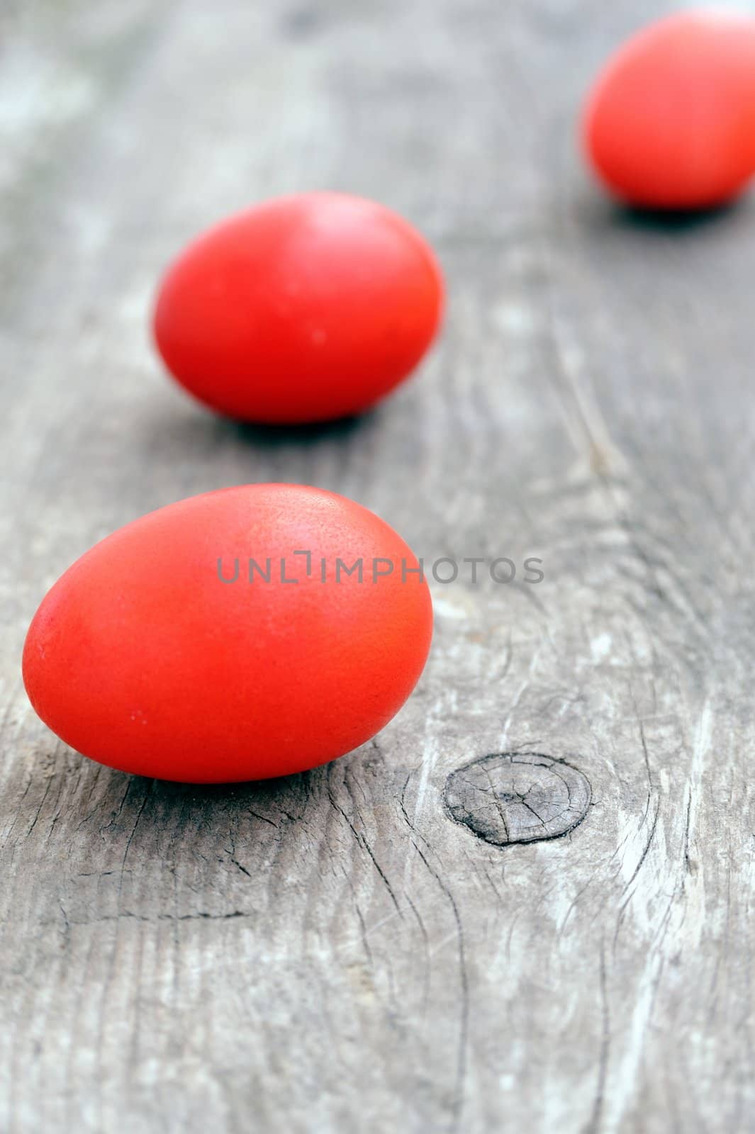 An image of three red Easter eggs on the wood