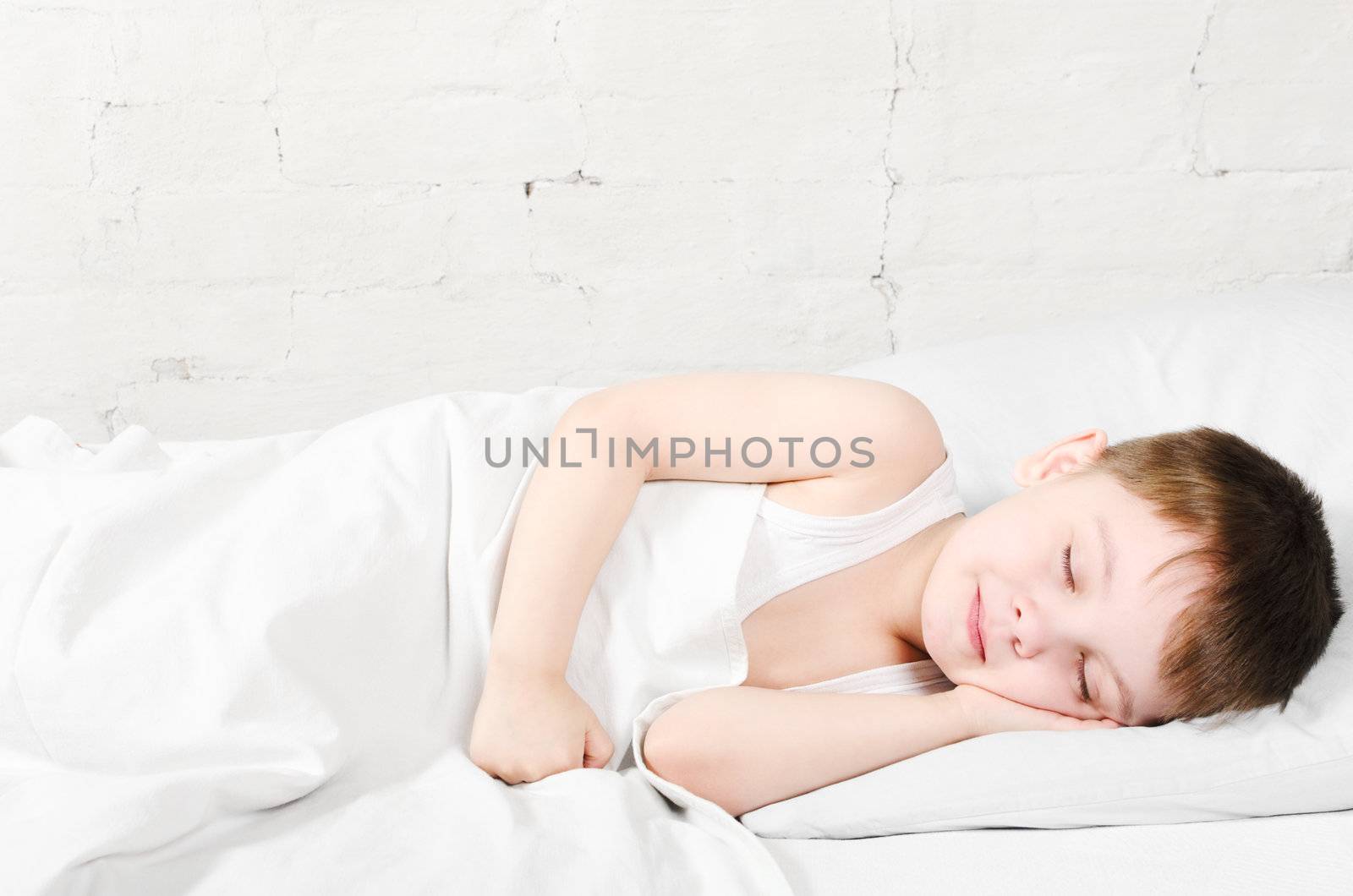 Small boy (4 years) is sleeping near the bright brick wall