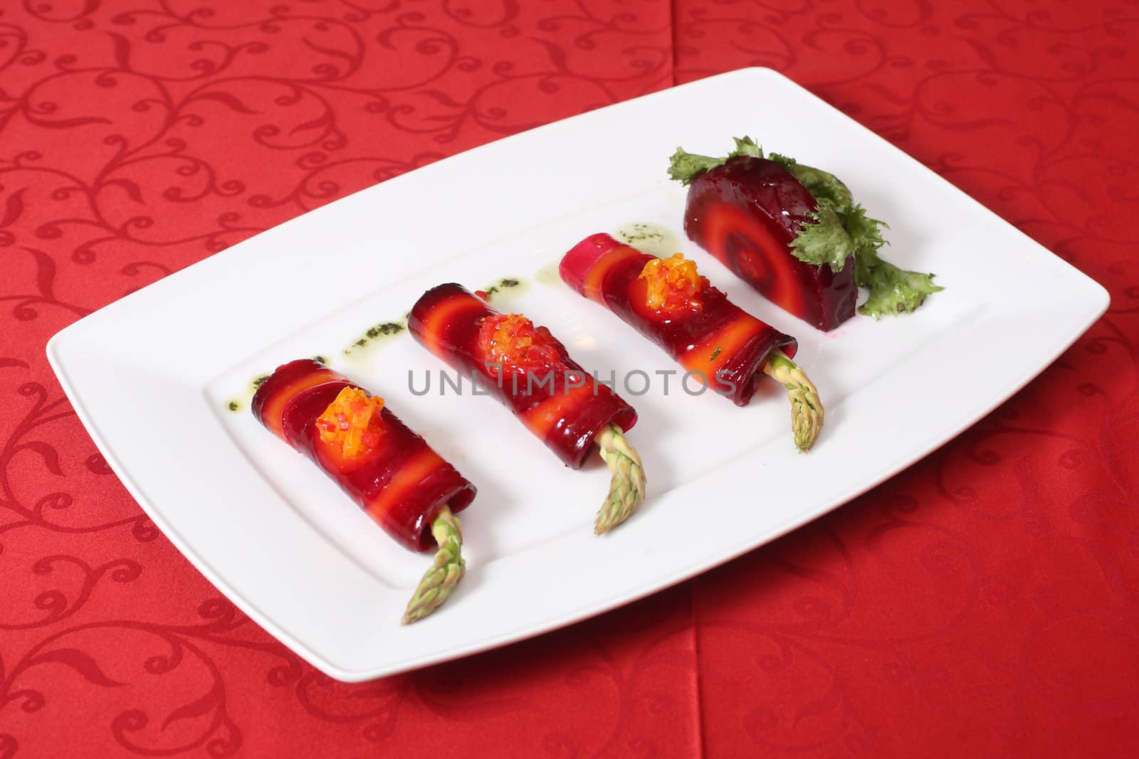 Vegetable rolls with asparagus and red beet on a white plate