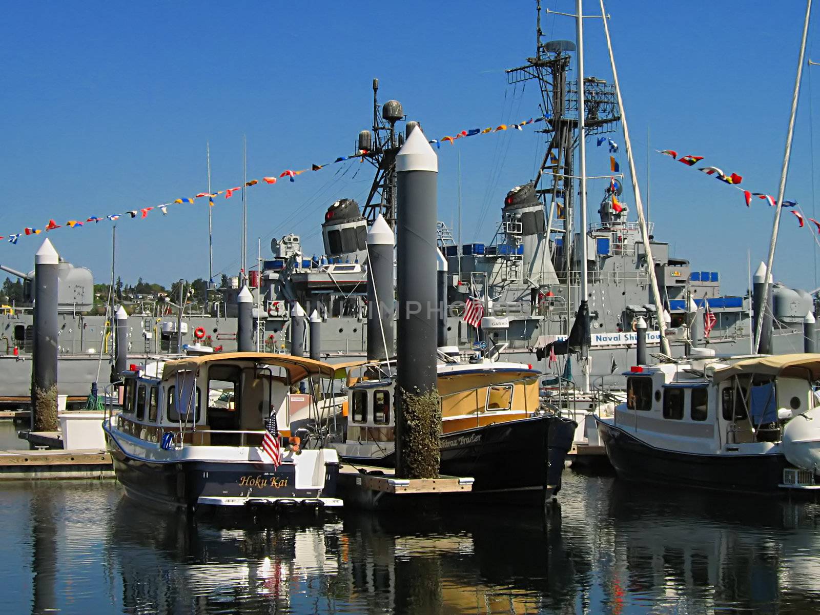 A photograph of a naval destroyer among smaller boats.