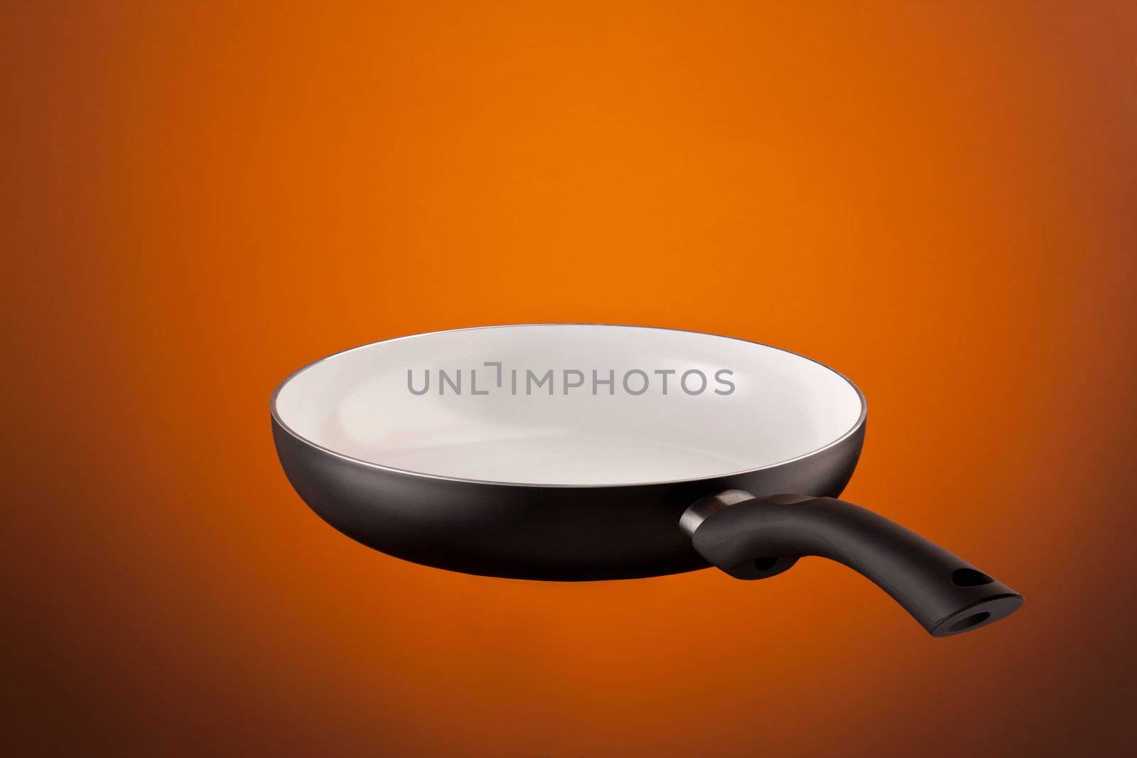 new ceramic frying pan over orange background