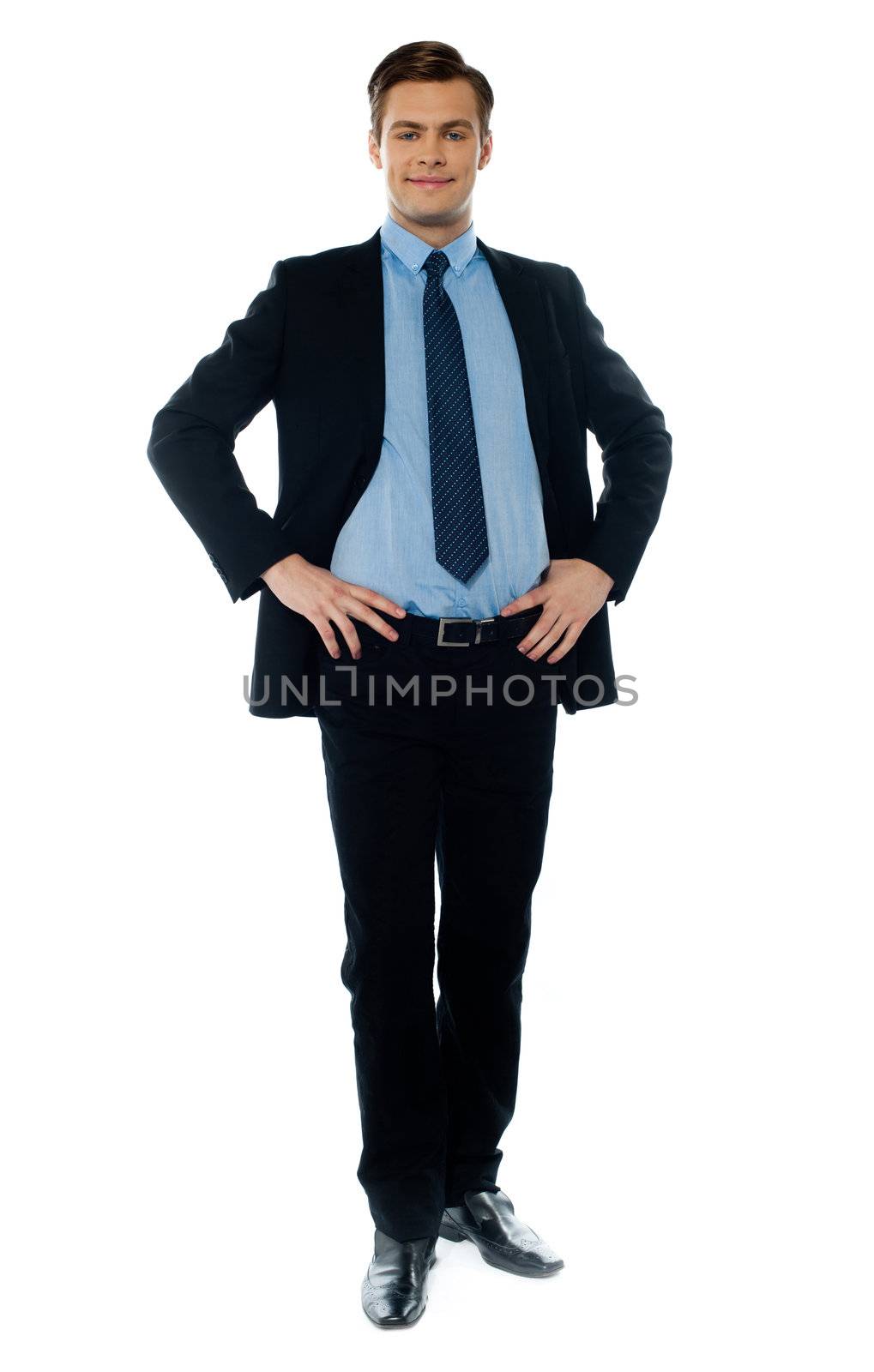Stylish young executive in business suit posing with hands on his waist