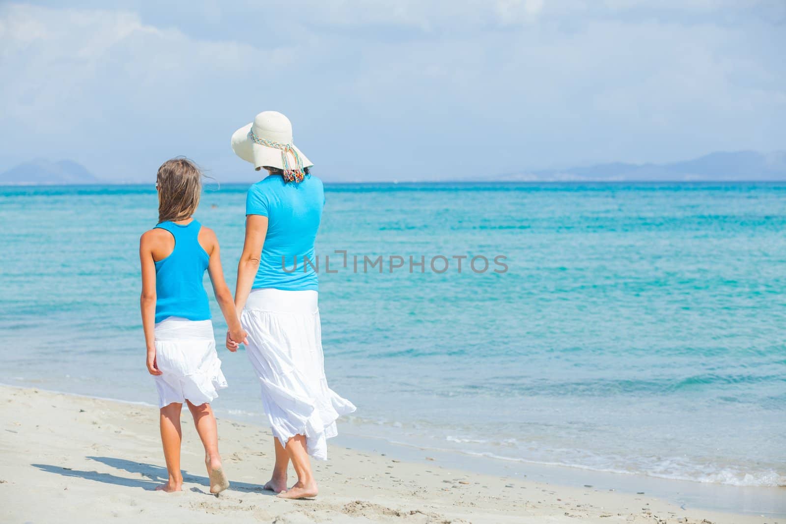 Back view mother and her daughter having fun on tropical beach