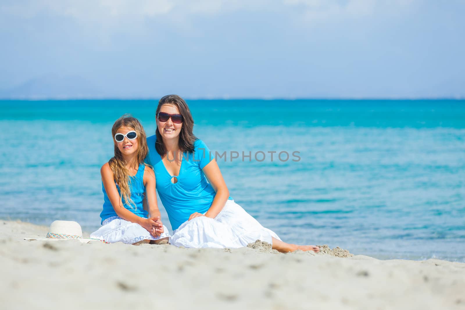 Young mother and her daughter on tropical white sand beach