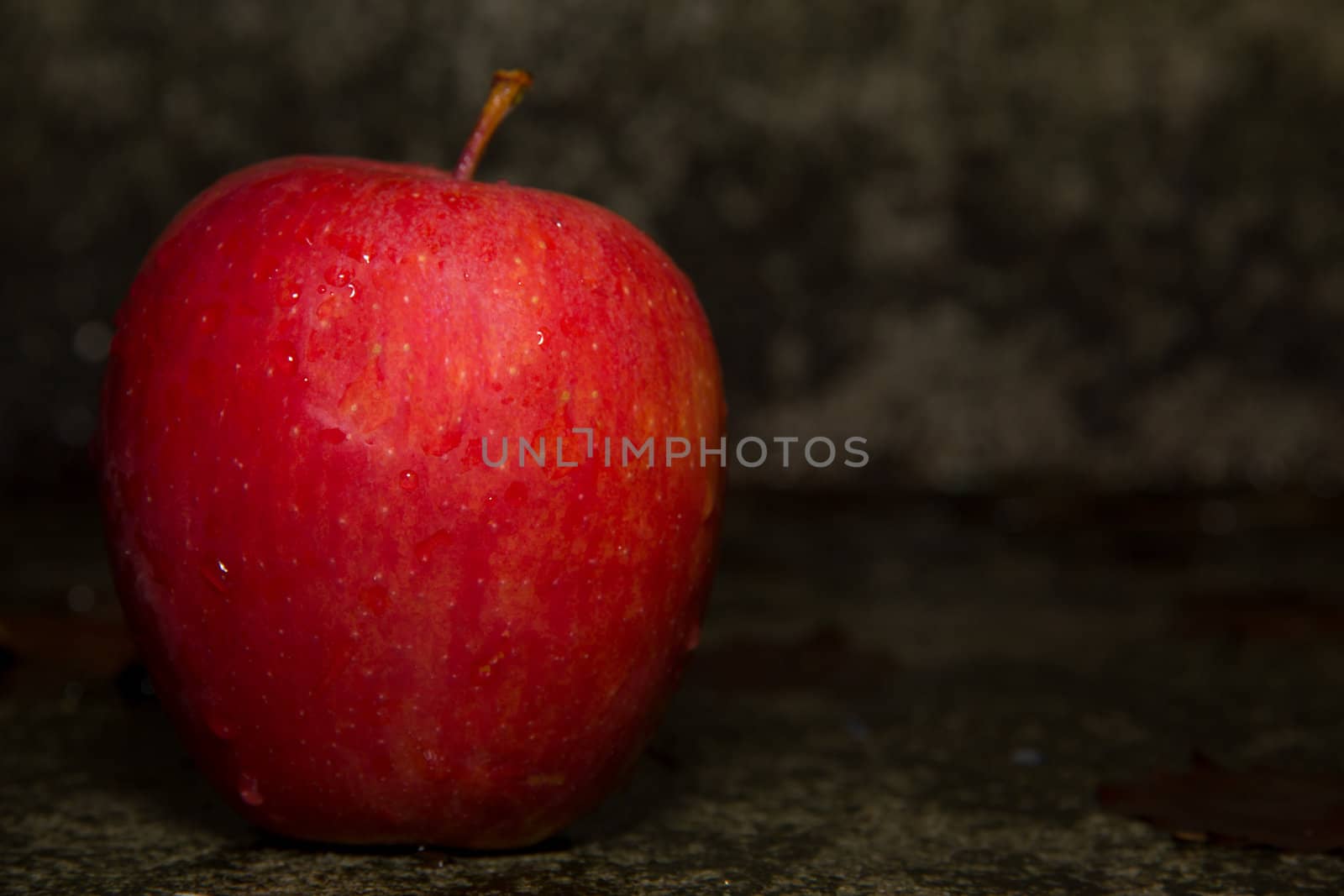 A picture of a red apple on concrete ground