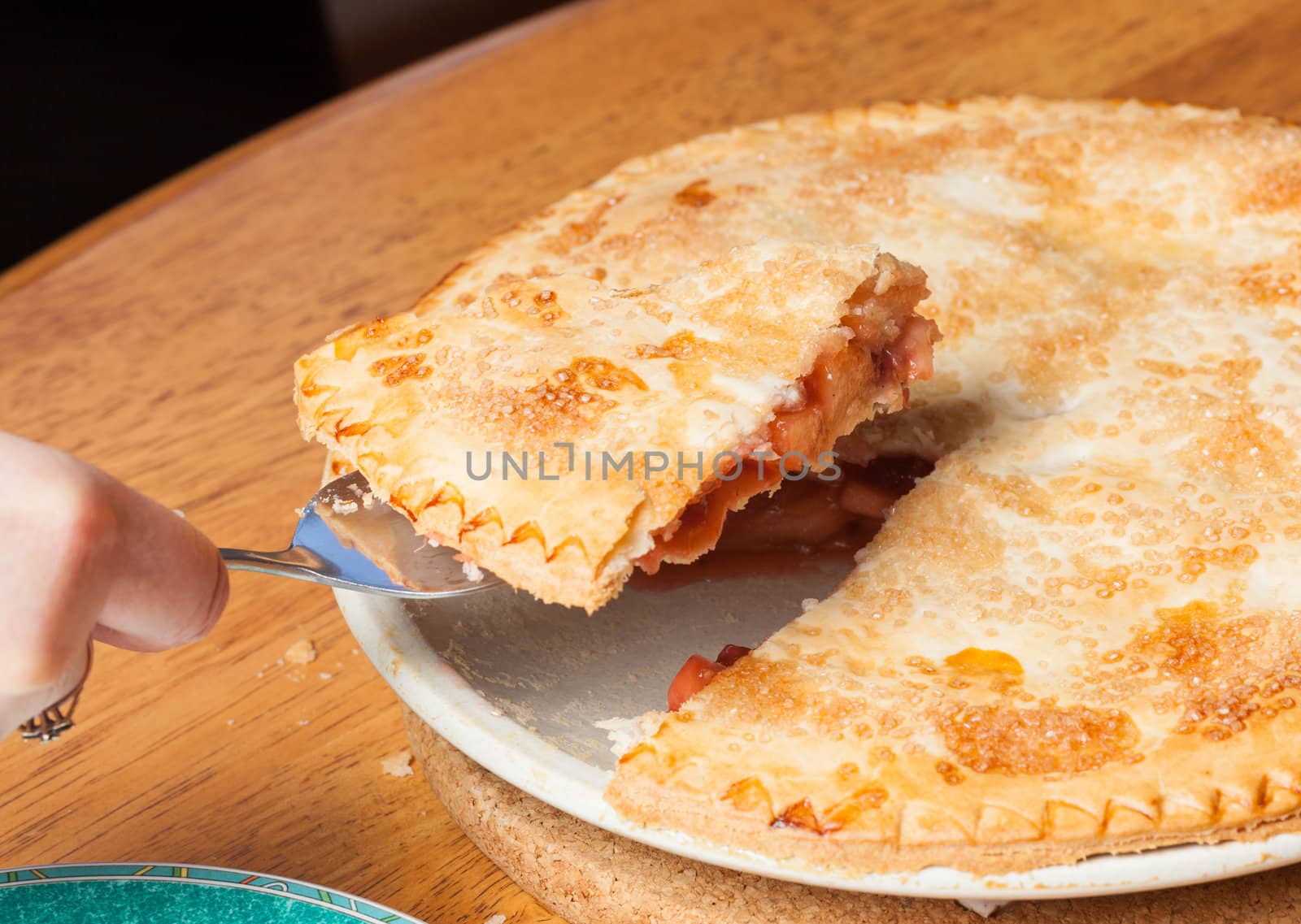 Home made baked fruit pie from oven and on table being cut with knife