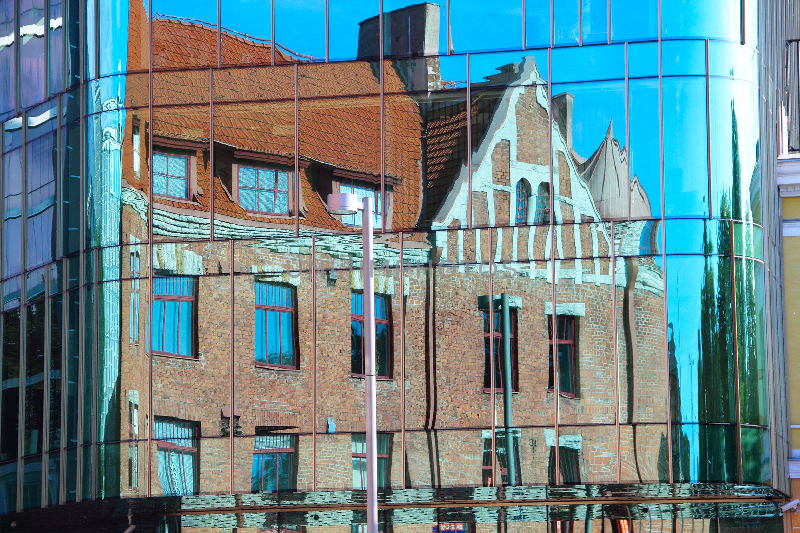 Reflection of old house in glass of new building by destillat