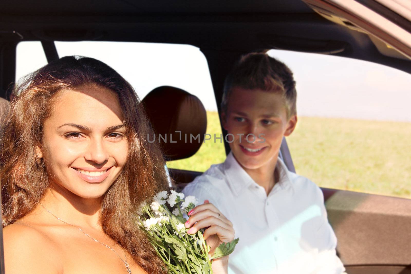 Young man and woman sitting in car and smiling