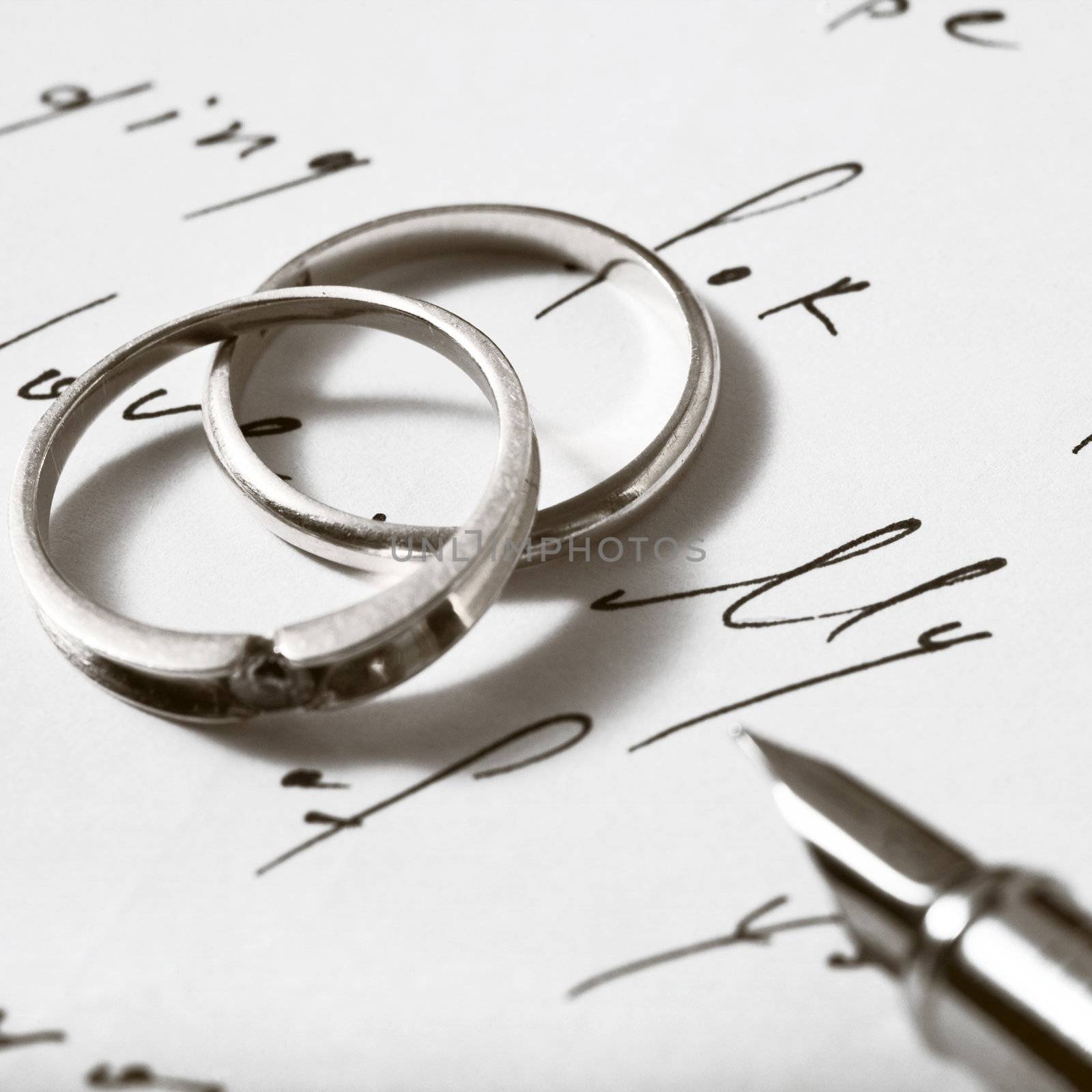 An image of two rings and a pen on a letter
