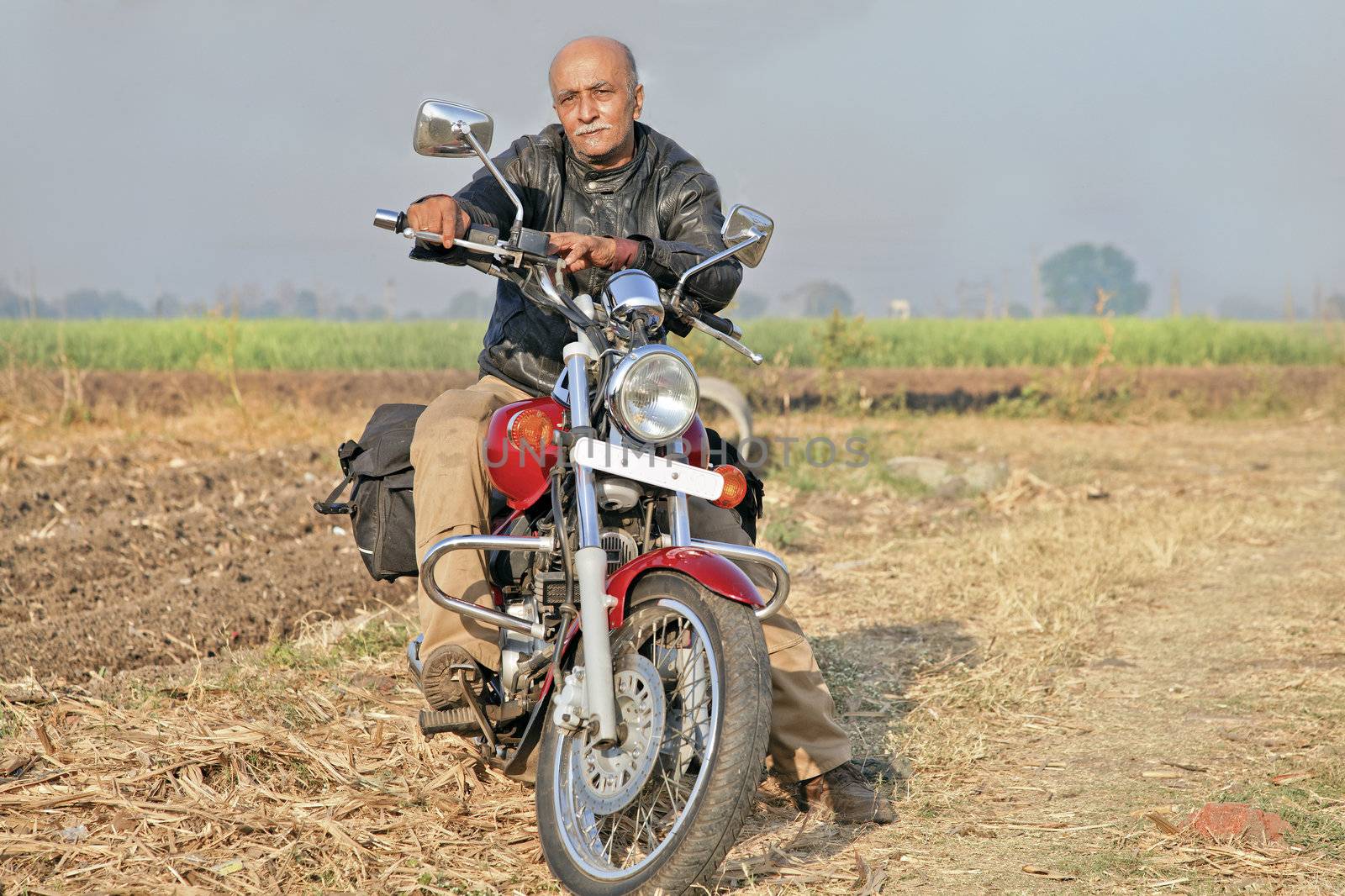 Gujarat India, Senior unshaven Indian male citizen on a red cruiser two wheeler  motorcycle