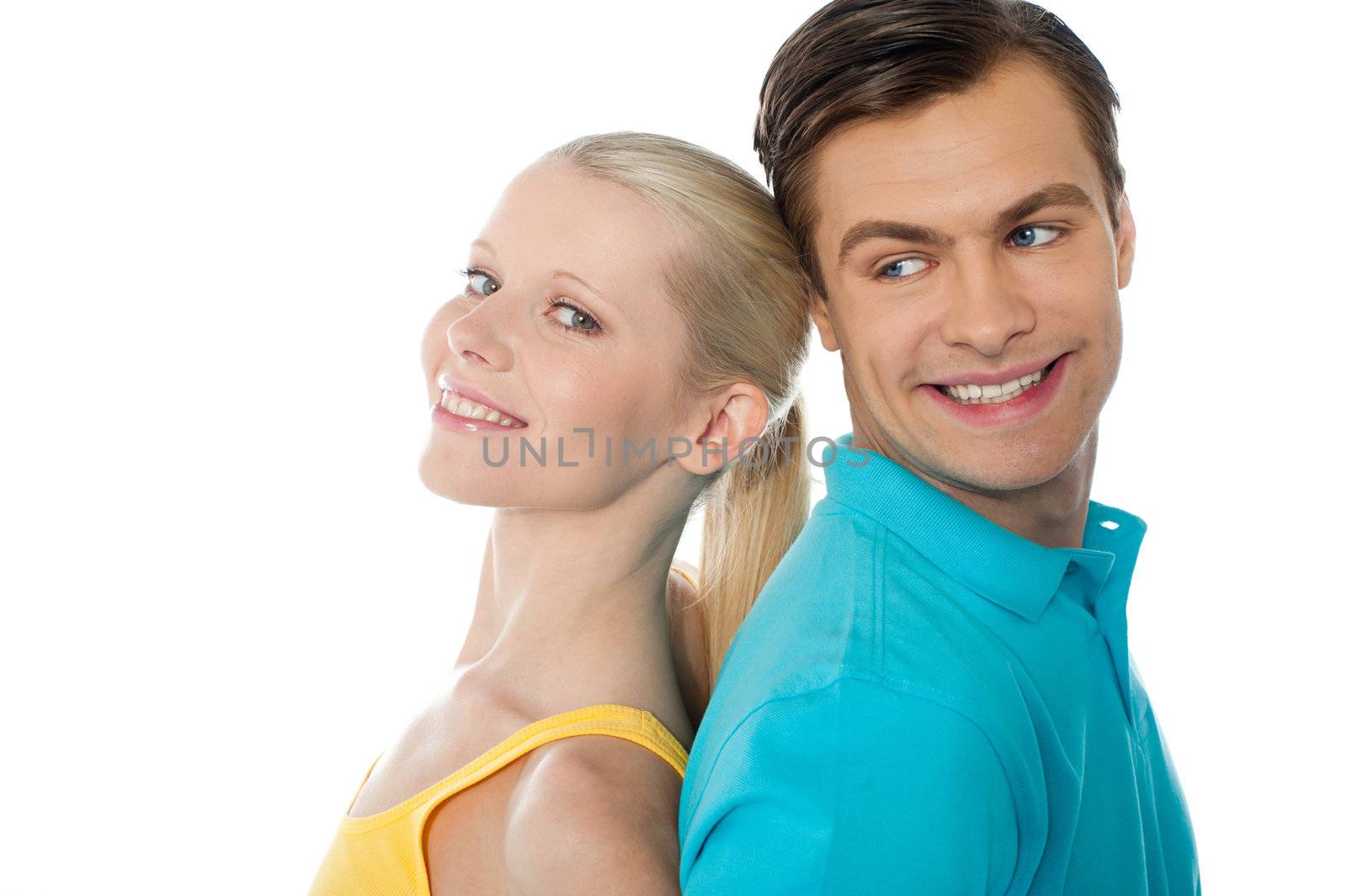 Beautiful young couple in love, posing back to back on white background