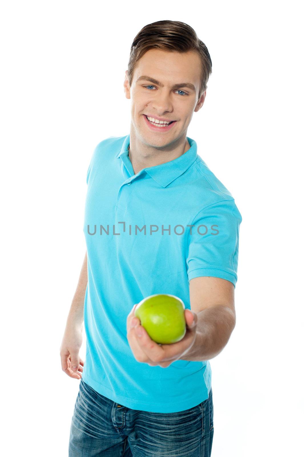 Good looking healthy guy offering a green apple isoalted over white background