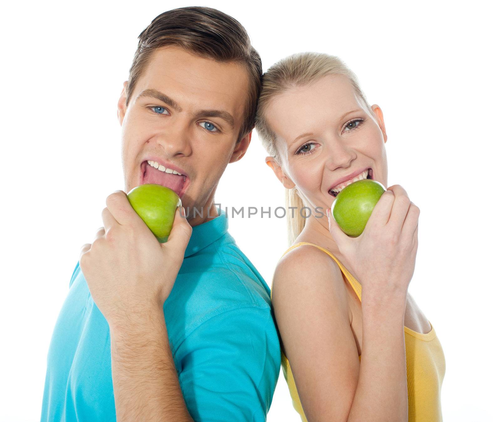Couple posing back to back with green apples on white background