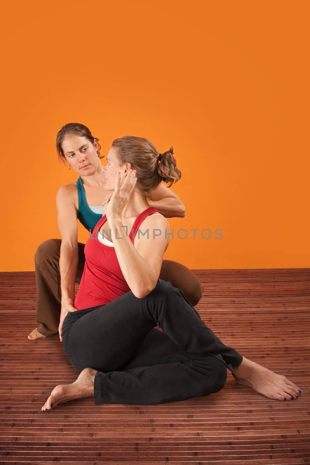 Yogasana trainer assisting student over orange background
