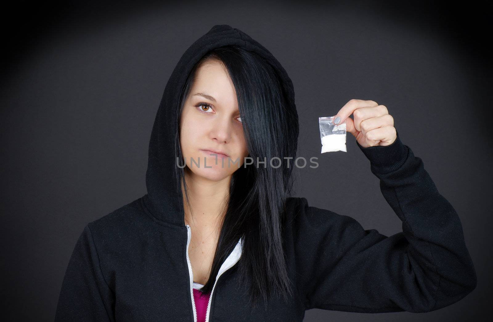 Gloomy portrait of a young woman or teen addict looking sad showing her little bag of drugs.