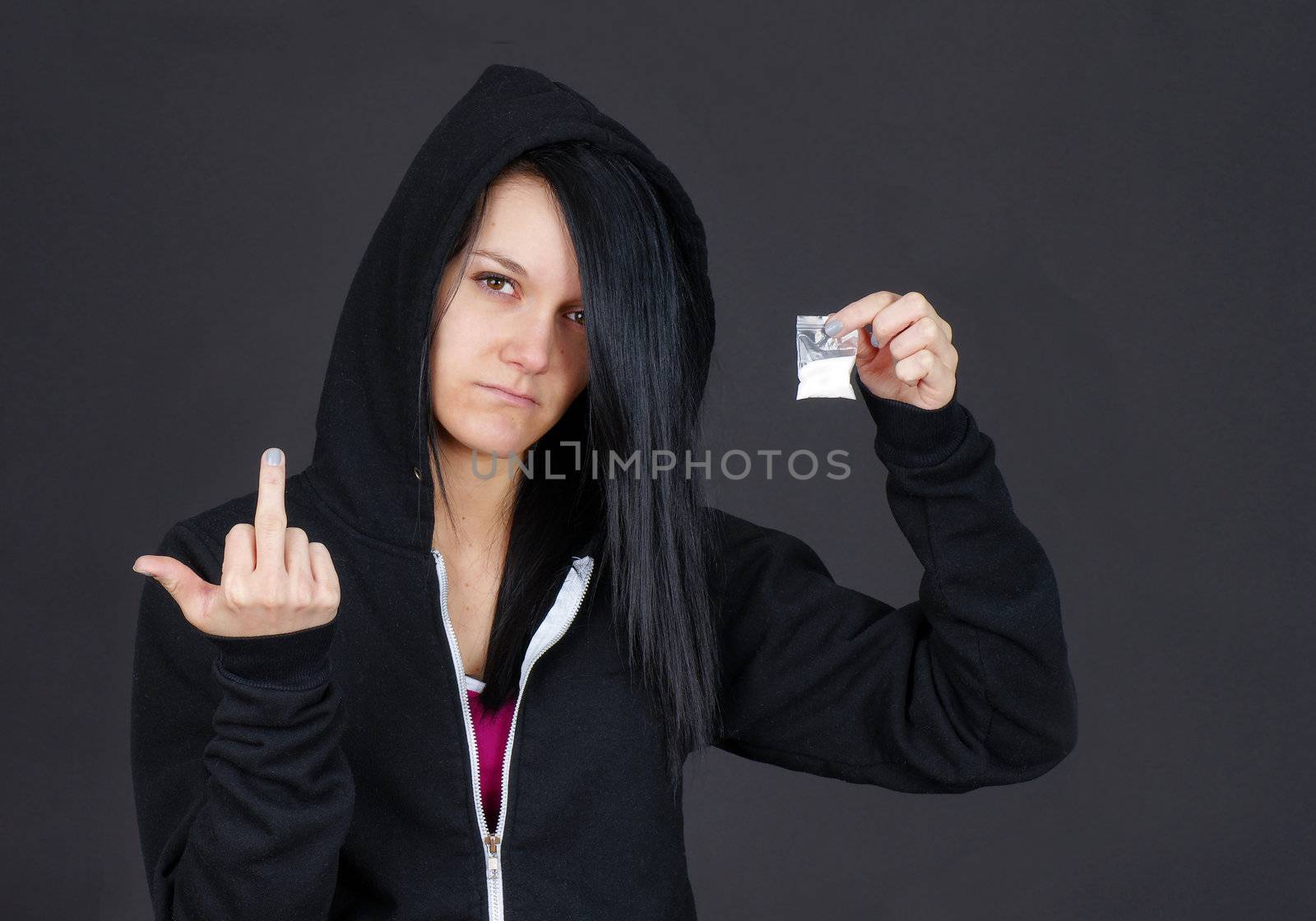 Young woman drug addict or dealer showing a packet of drugs and givng the viewer the finger.